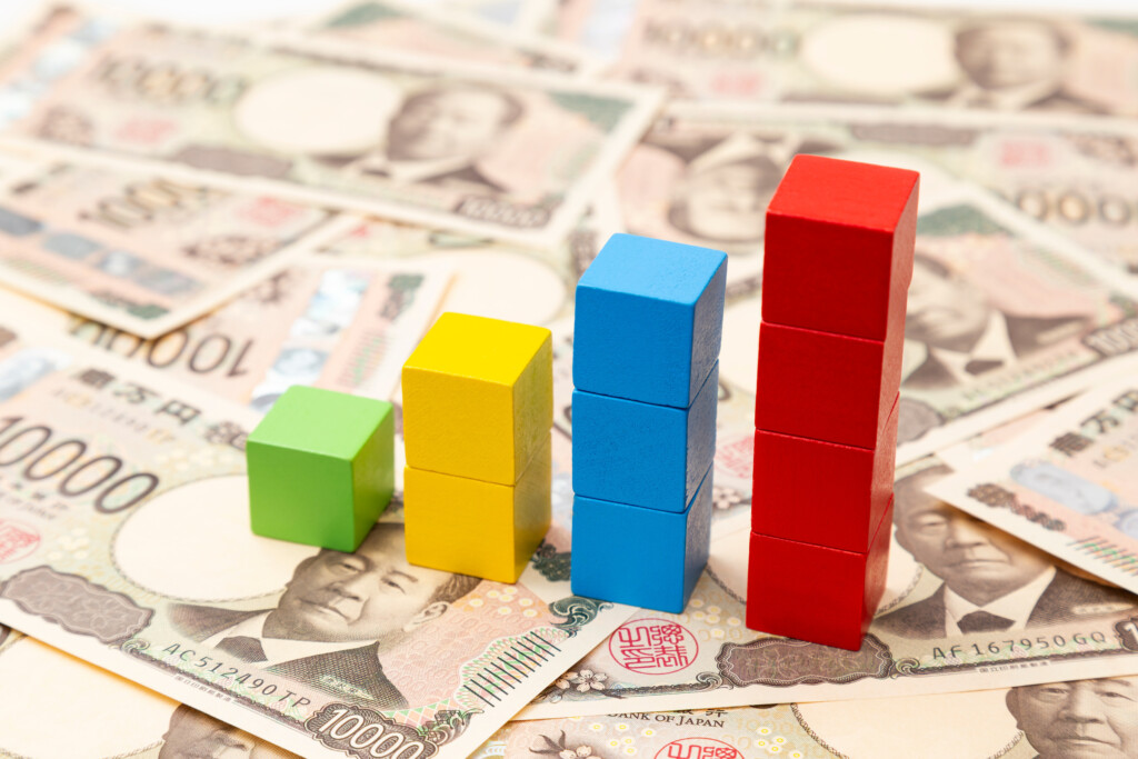 積み木のグラフと紙幣で表す賃金上昇のイメージ