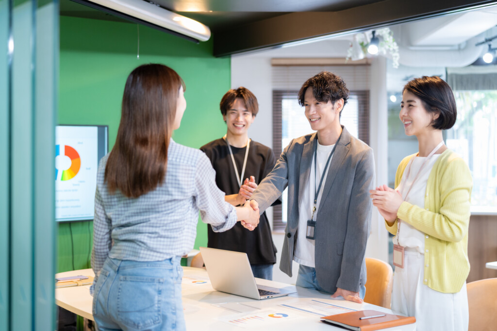 オフィスで笑顔で握手をする社員たち